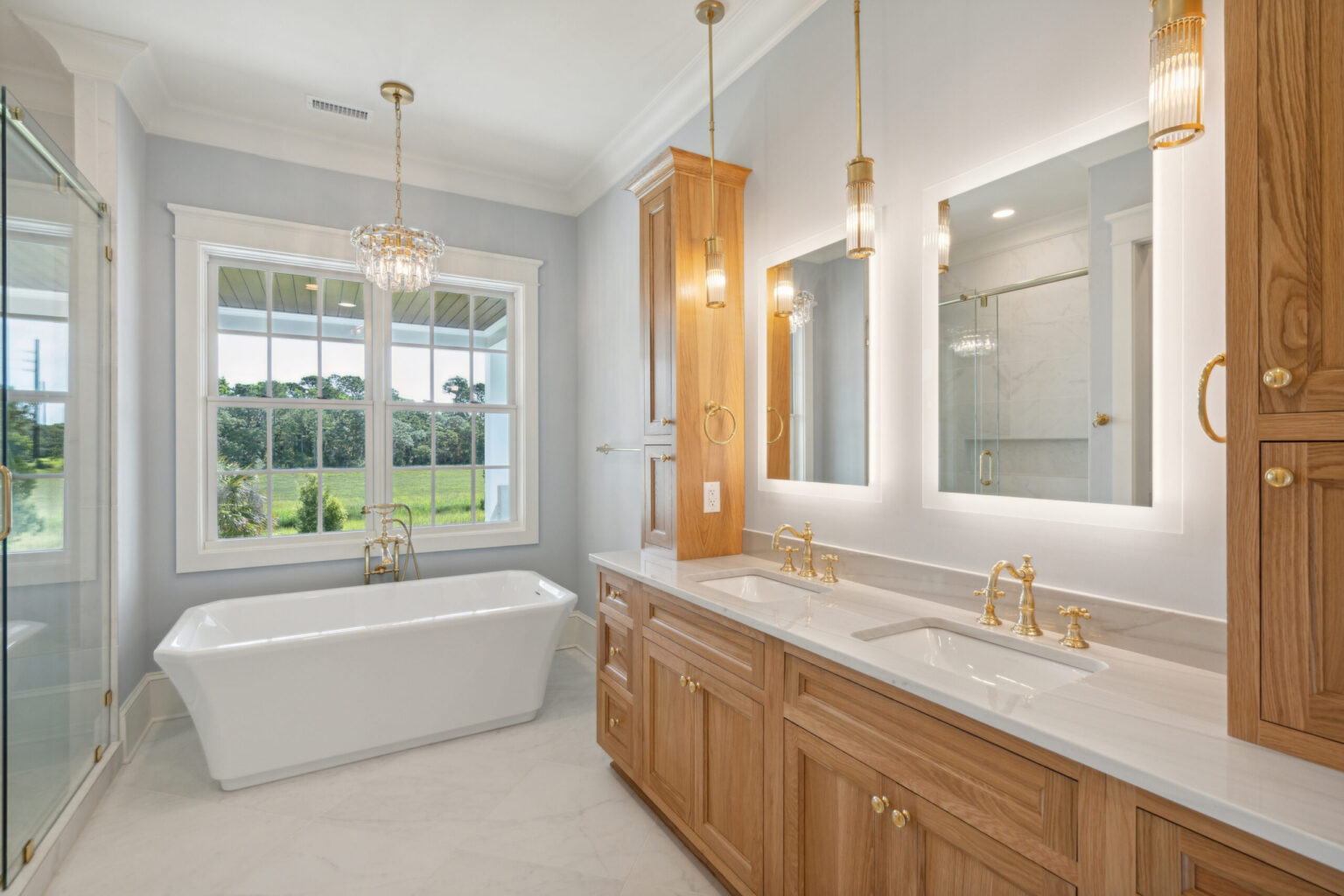 Integrity Cabinets custom bathroom vanity with warm oak shaker cabinets, double sinks, and brass hardware.