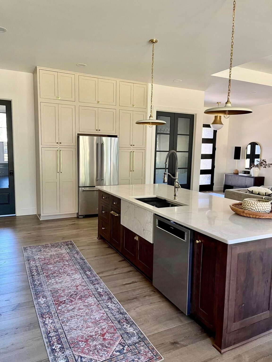 Integrity Cabinets custom kitchen design featuring warm cream wall cabinets, a built-in stainless steel refrigerator, and a dark wood island with marble countertops.